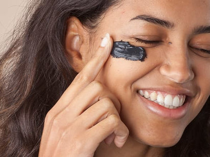 Woman applying a charcoal face mask