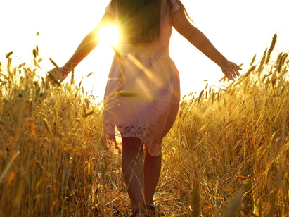 Woman walking through sunny field