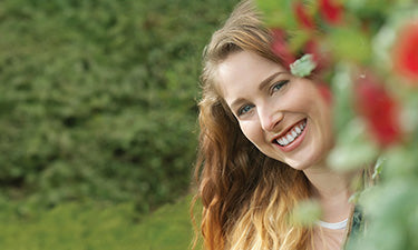 image for fluoride toothpaste category featuring woman smiling in garden