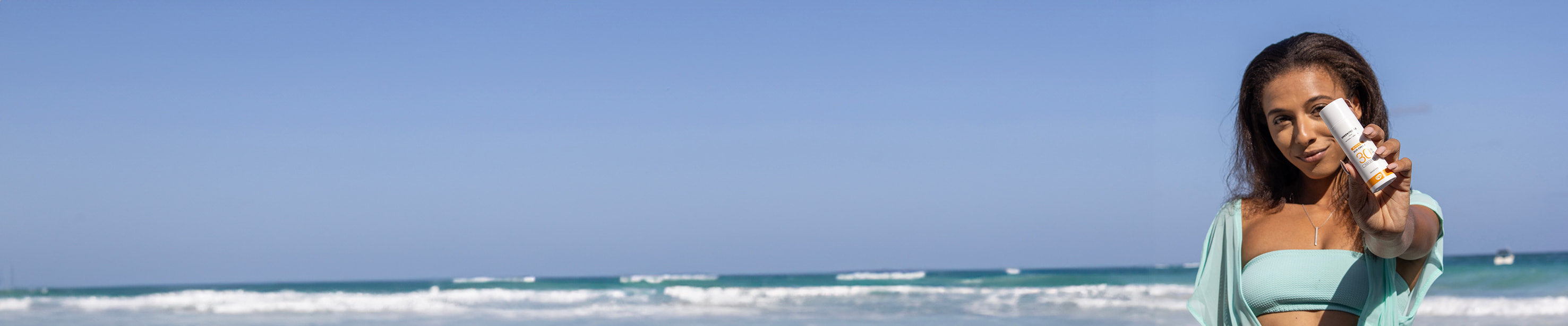 woman on beach holding non comedogenic sunscreen