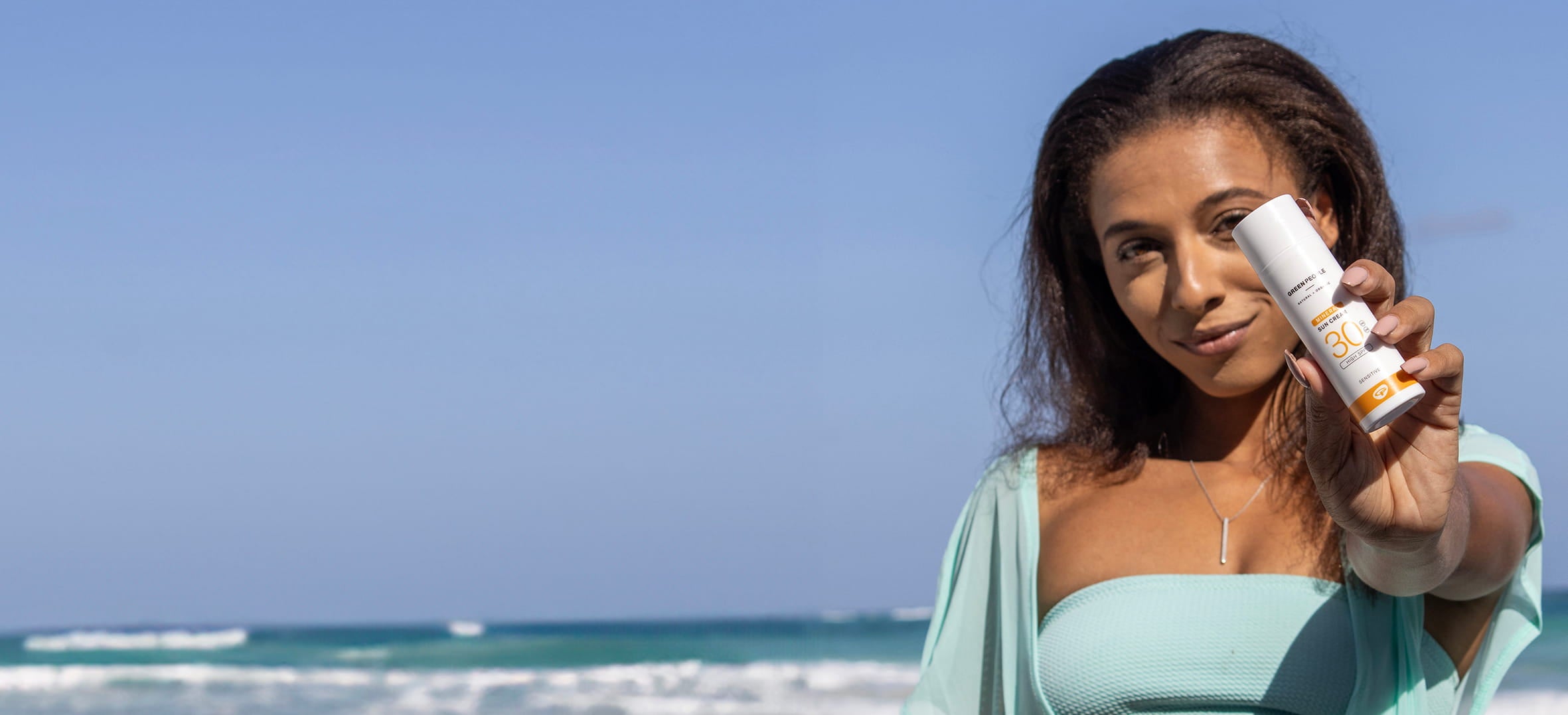 woman on beach holding non comedogenic sunscreen