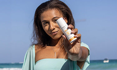 woman on beach holding non comedogenic sunscreen