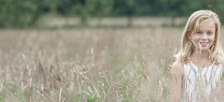 banner for organic children category featuring girl standing in field of long grass