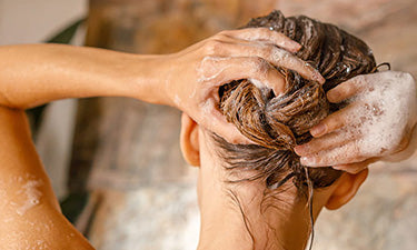 banner for natural and organic shampoo category featuring woman washing hair