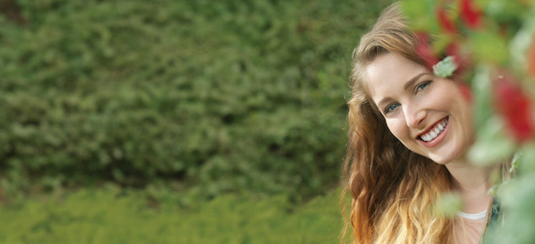 banner for natural and organic toothpaste category with lady smiling in garden