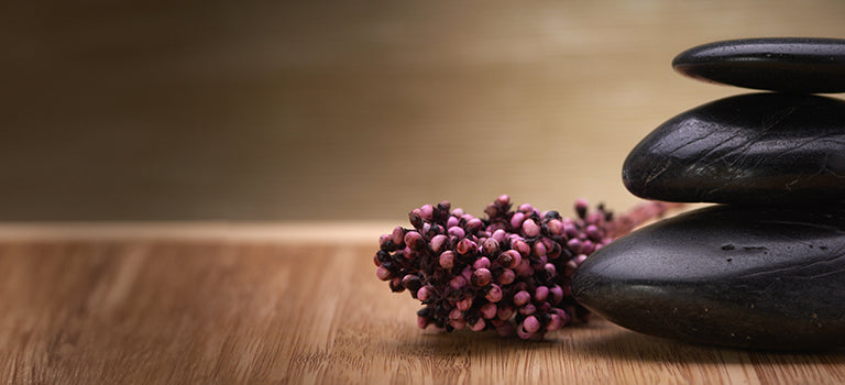 image for self care essentials category featuring smooth black pebbles and pink berries