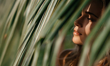 banner for vegan shampoo and conditioner featuring woman looking through leaves